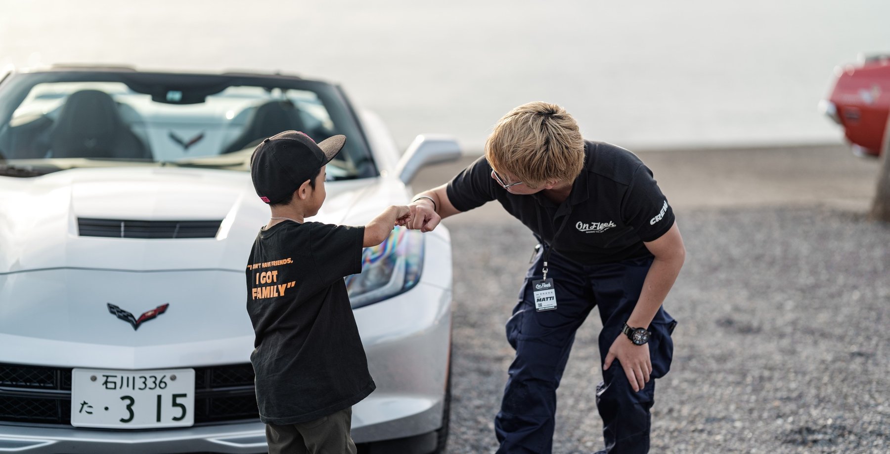 コルベットの前で子どもとグータッチを交わすスタッフ